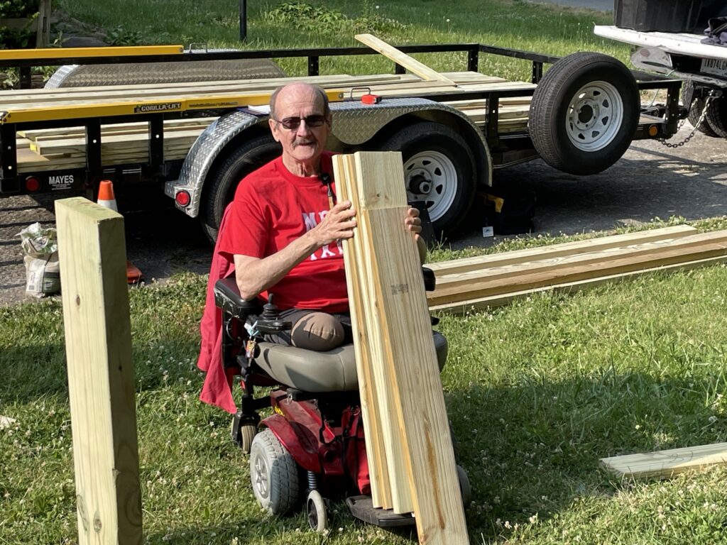 Milton using his power scooter to help SAWs build a ramp at his home.