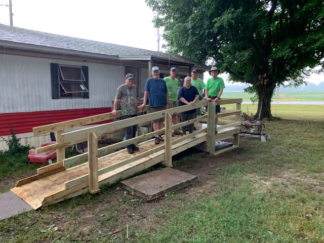 Volunteers standing on wooden wheelchair ramp